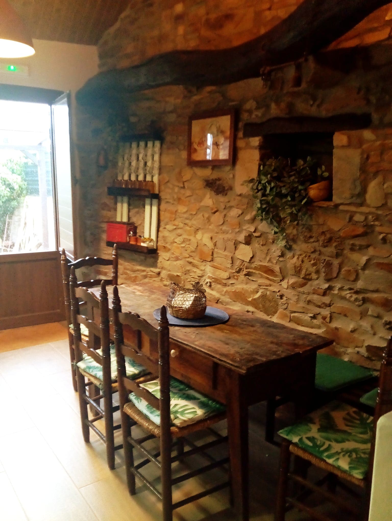 El comedor, con su mesa de madera y el muro de piedra vista