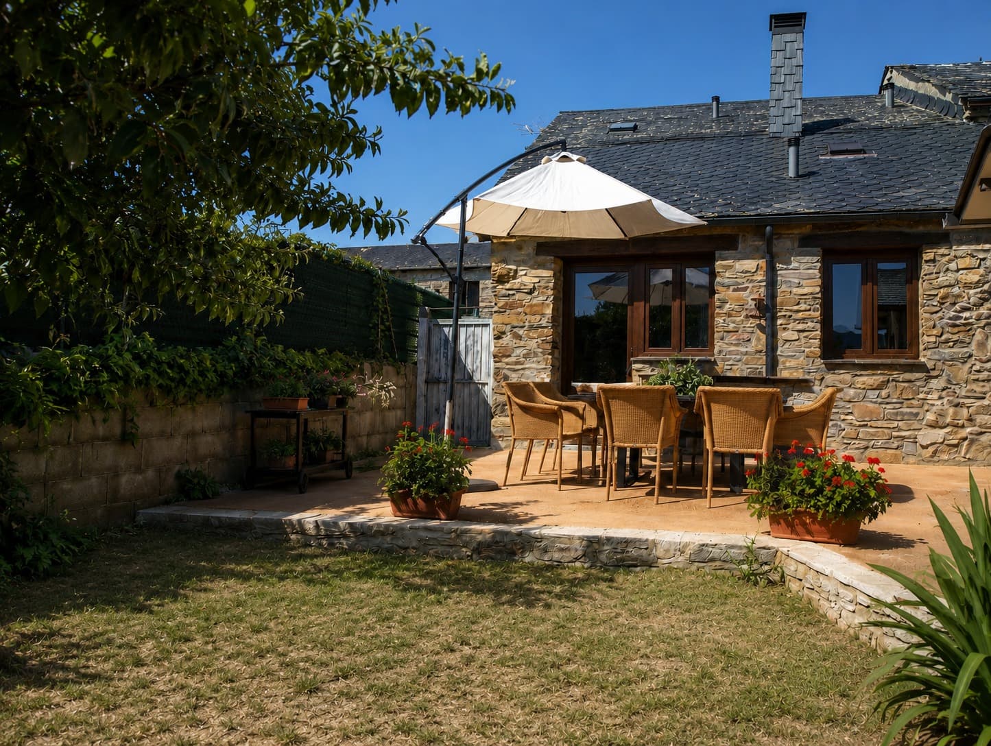 Casa de piedra con tejado de pizarra y terraza con jardín del albergue Edén del Acebo