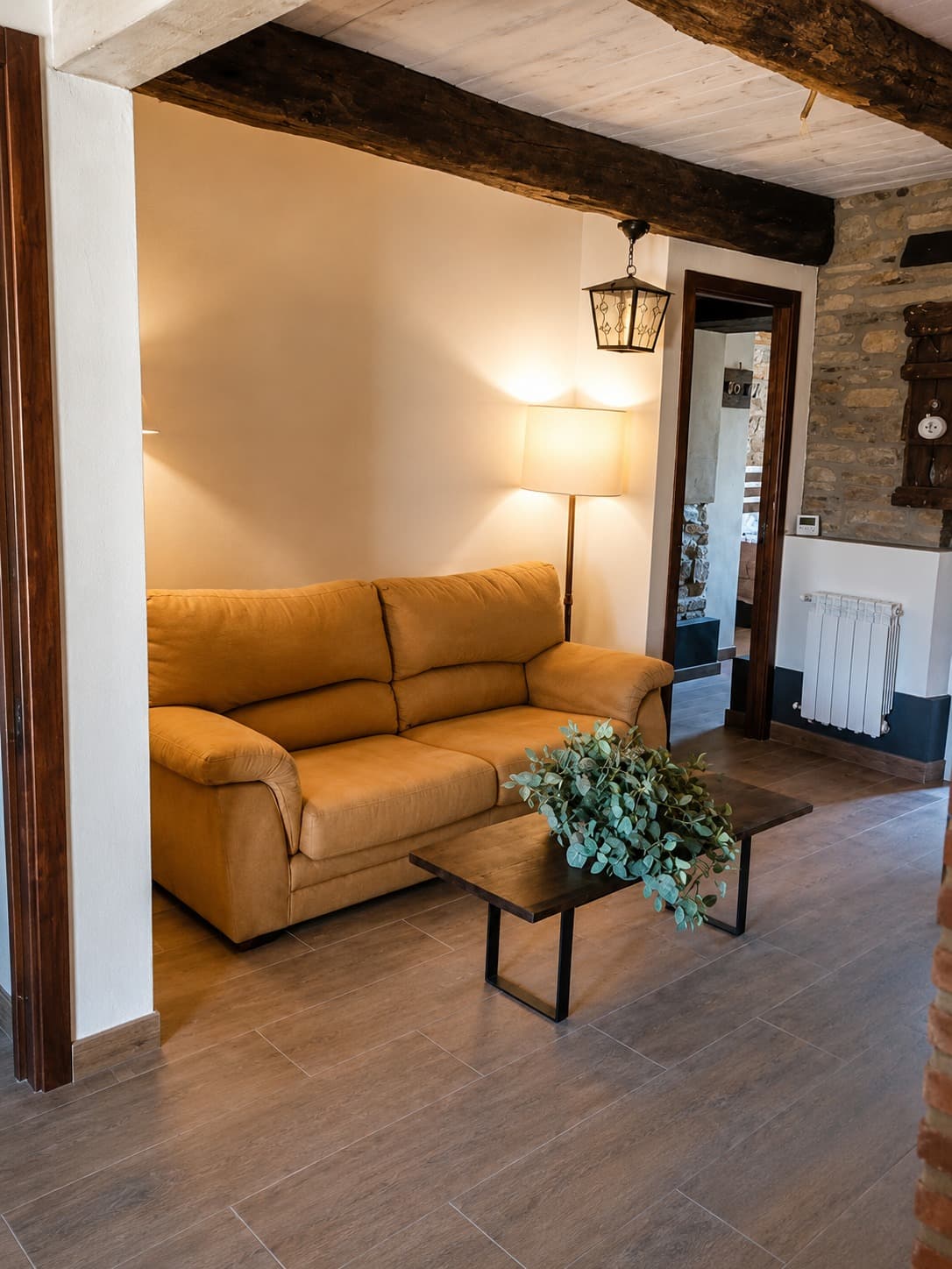 Interior del albergue con vigas de madera vistas y muros de piedra